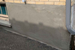Concrete wall with a slight slope on a street, showing signs of wear and a shadow.