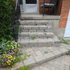 Step-by-step stone pathway leading to a house with plants on the side.