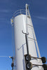 Vertical white steel storage tank with external ladder, safety cage, and mounted transport wheels against a clear blue sky, industrial liquid storage silo