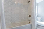 Bathroom with white subway tile shower walls and bathtub combination featuring brushed nickel shower fixture