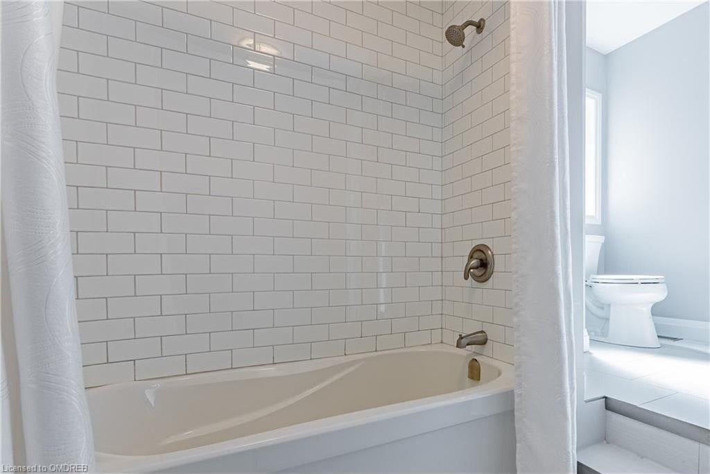Bathroom with white subway tile shower walls and bathtub combination featuring brushed nickel shower fixture